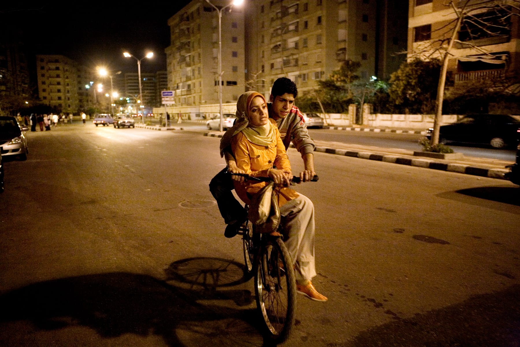 En kvinna och en man delar en cykel på en lugn gata i Alexandria på natten. Foto: Emelie Asplund